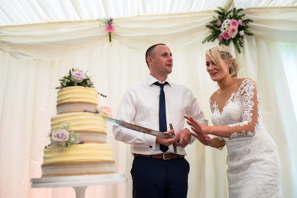 Traditional wedding photograph of paul and Lexy cutting their wedding cake