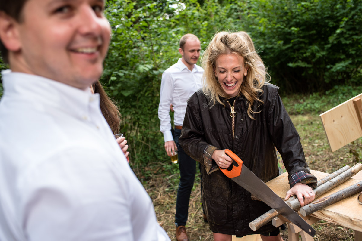 Photograph of wedding guest sawing wood at Seb and Brogans Kent wedding celebration