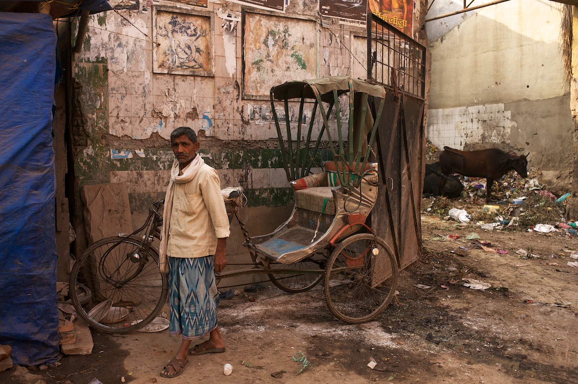 Photograph of man standing next to rickshaw in Varanasi