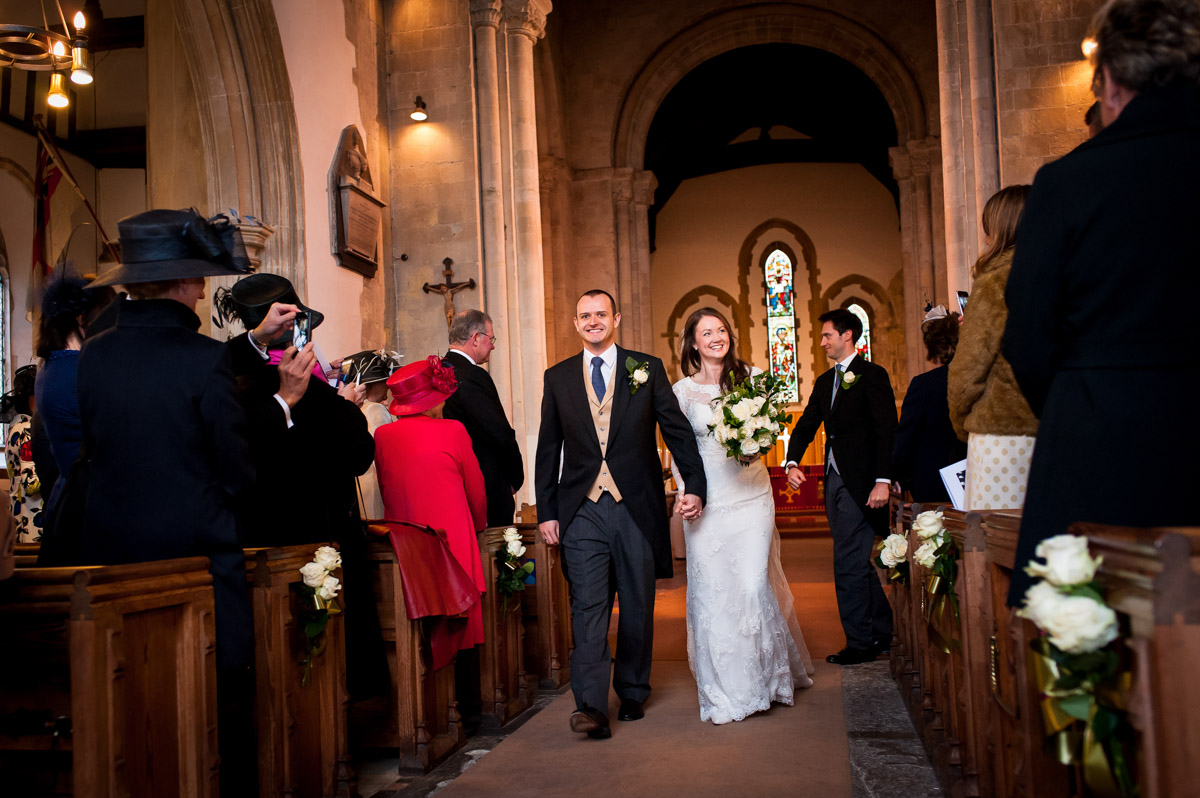 Photograph of Emma and Ollie walking back down then aisle after their wedding ceremony