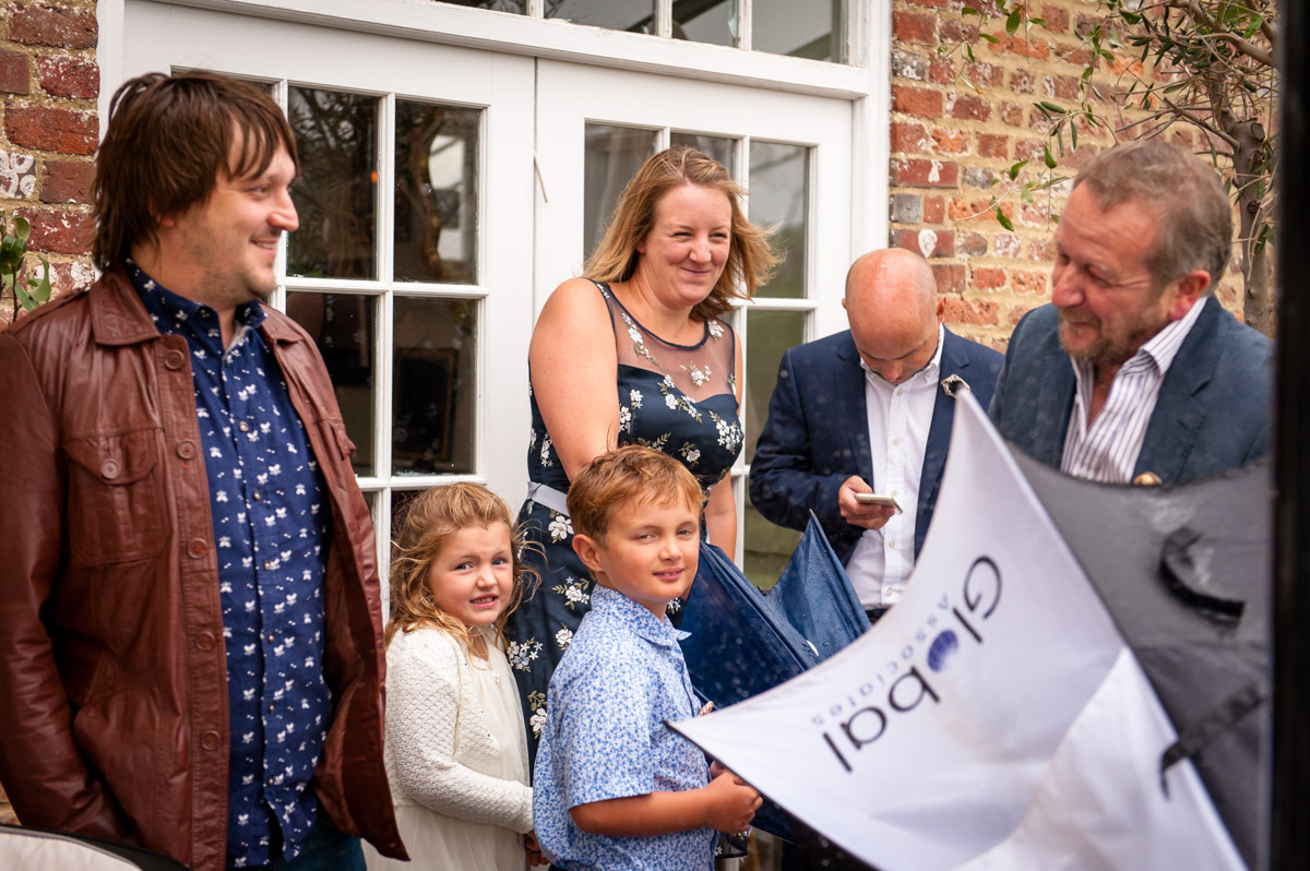 Photograph of rachel and daniels wedding guests in the rain at the Secret garden