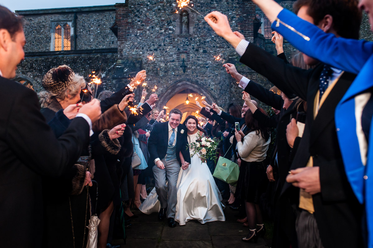 Marcus and Frances are photographed running under lit sparklers after their Kent wedding ceremony