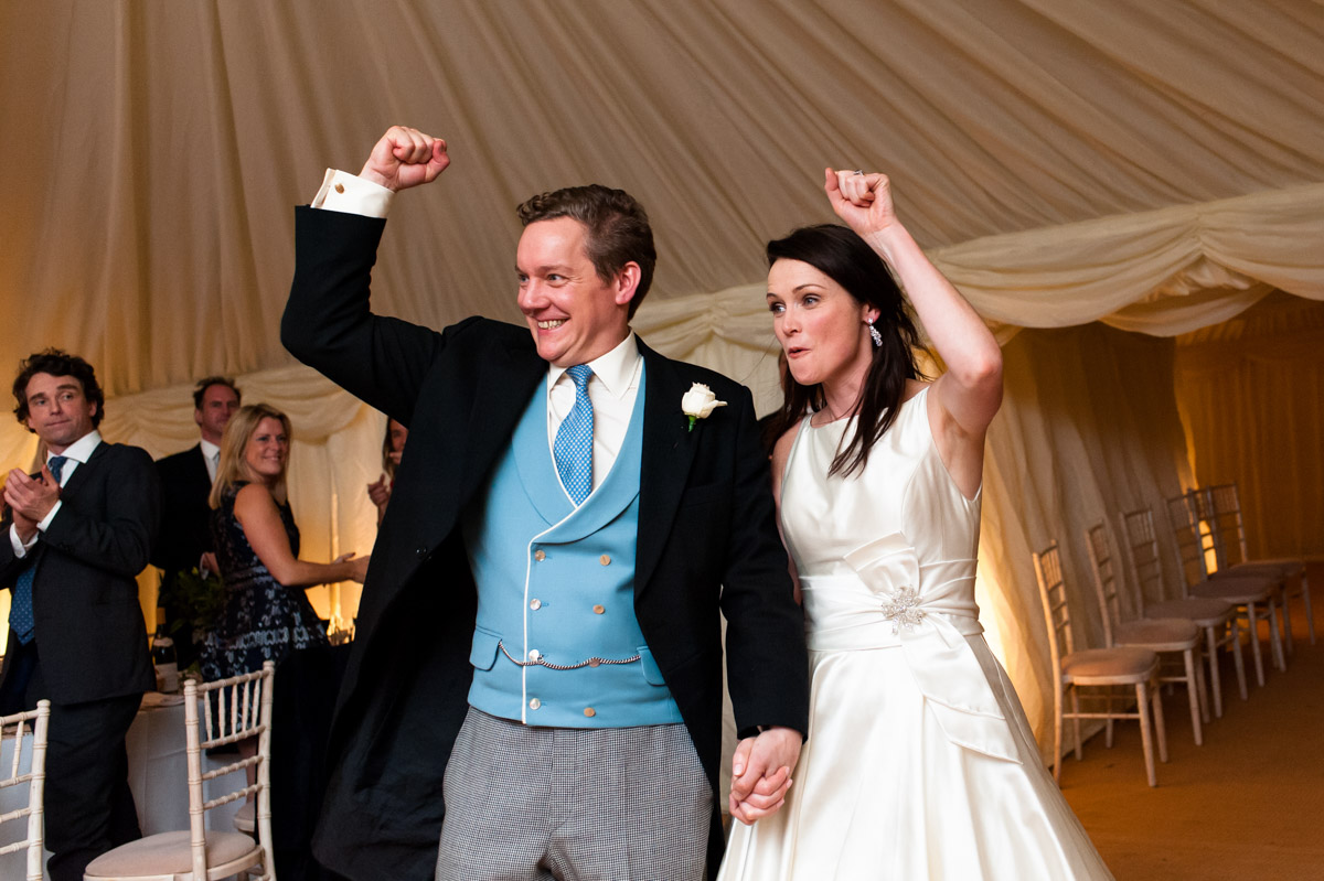 Frances and Marcus photographed as they are welcomed in for their reception wedding breakfast