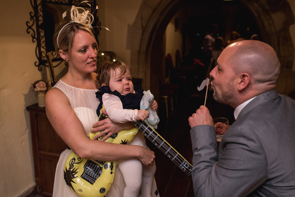 Guests are photographed at Lianne and Johns wedding reception messing with funny props