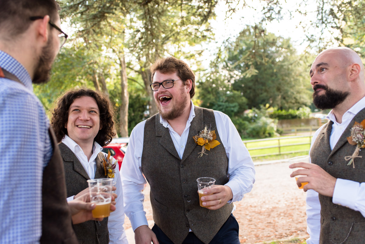 Groomsmen share a joke with paul on his wedding day at kent venue Chilham Village Hall