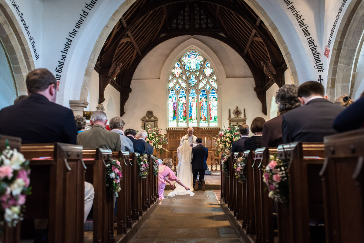 Brenchley Kent wedding photography of bridesmaid adjusting brides wedding dress