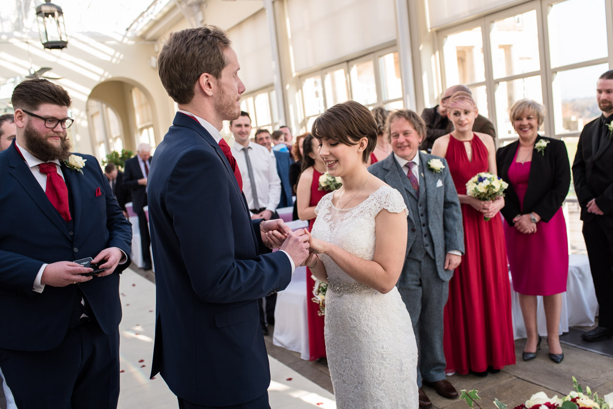 Buxted Park Hotel wedding. Photograph of Joe placing wedding ring on Bennets finger