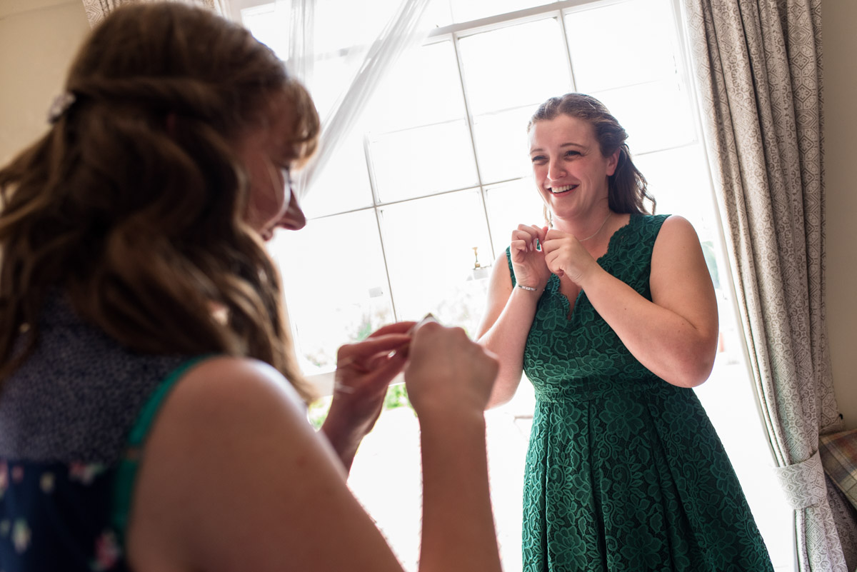 Bridesmaids put on neckless before Beth and Toms Ratsbury Barn wedding in Kent
