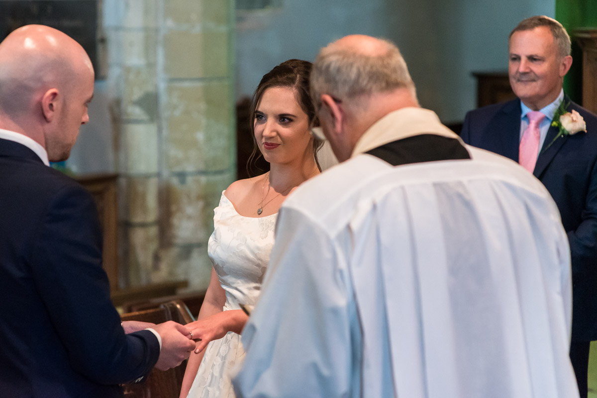 Photograph of Tom placing wedding ring on Emily