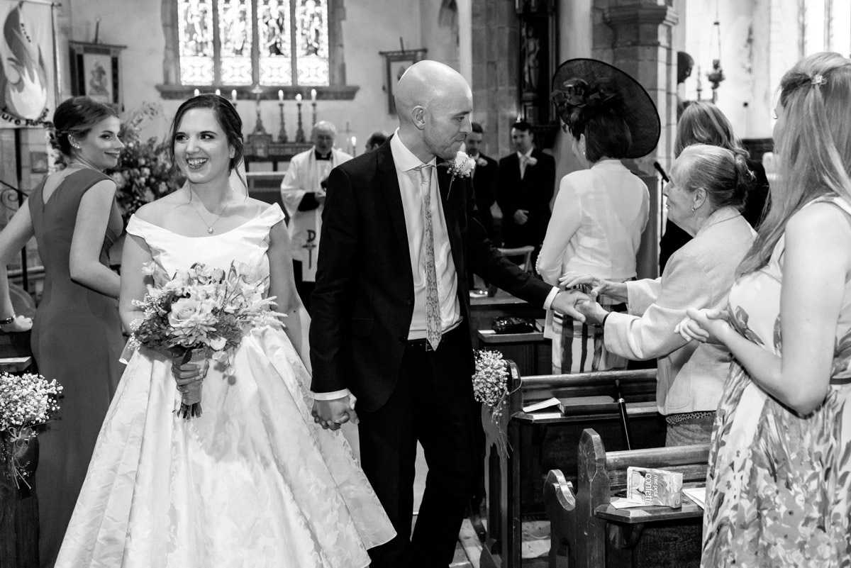 Emily and Tom photographed walking down the aisle after their wedding ceremony