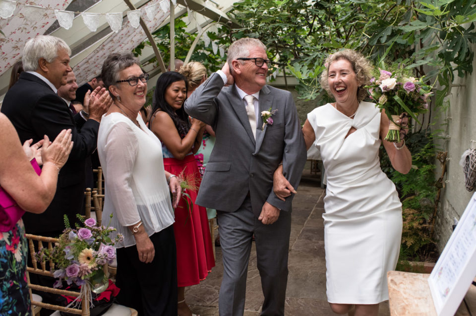 The Secret garden wedding photography of Kate and John dancing down the aisle
