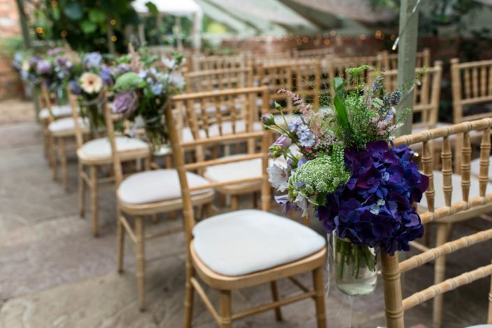 Summer garden flowers in jam jars at wedding at The Secret garden wedding venue