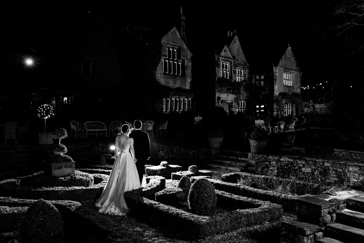 bride and groom walk through gardens at holdsworth house