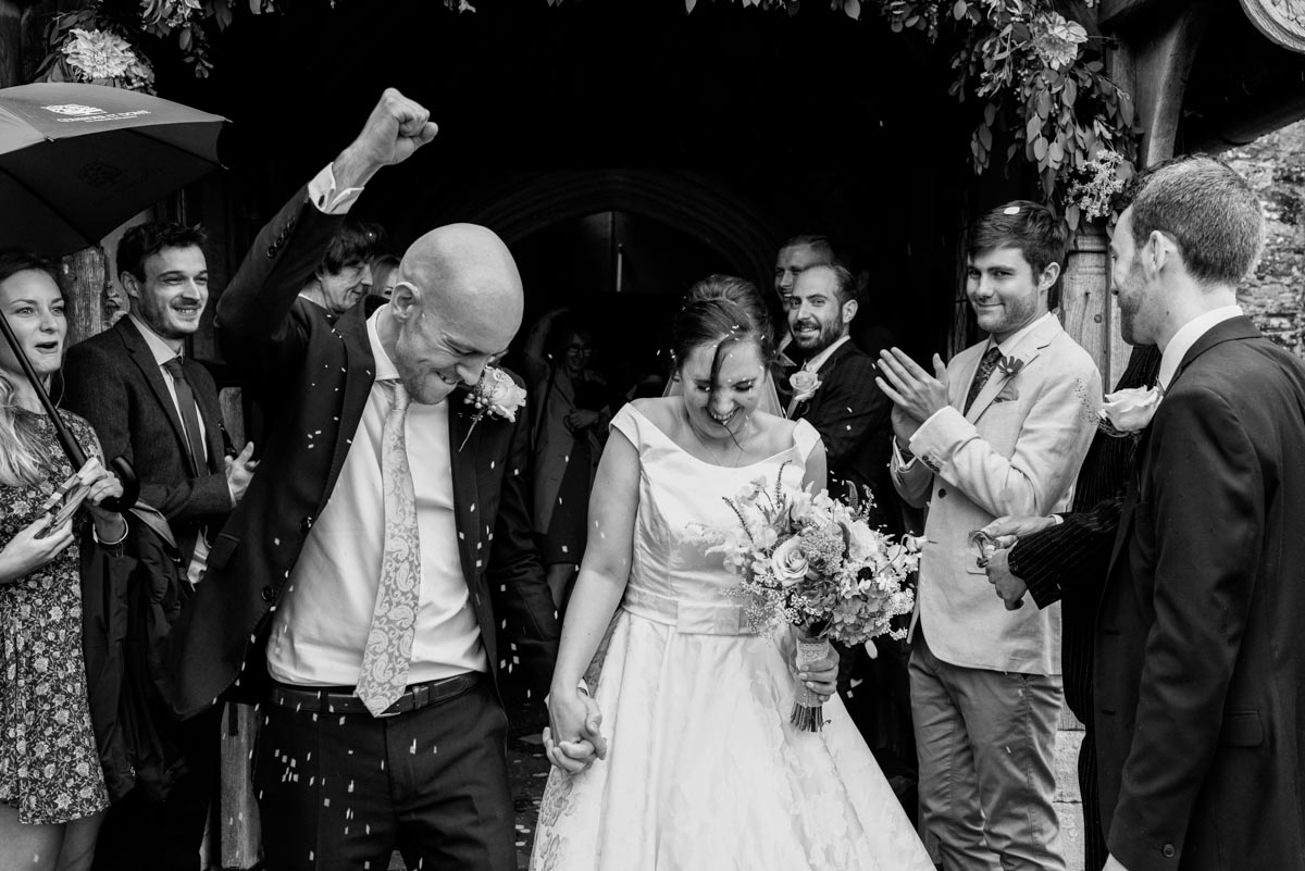 Bride and groom leave church after their Kent wedding and groom punches air
