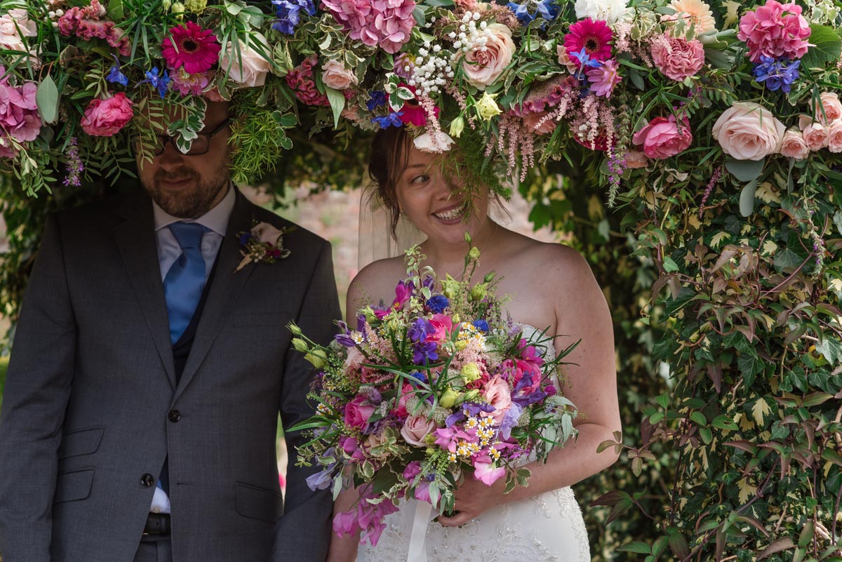 Flowers at the secret garden wedding venue almost cover the bride