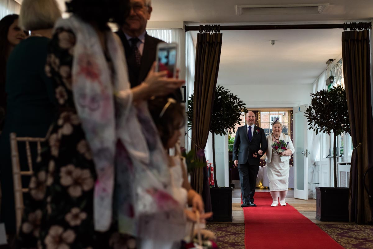 Jo escorted by her son to the Orangery on her wedding day at chilston park hotel