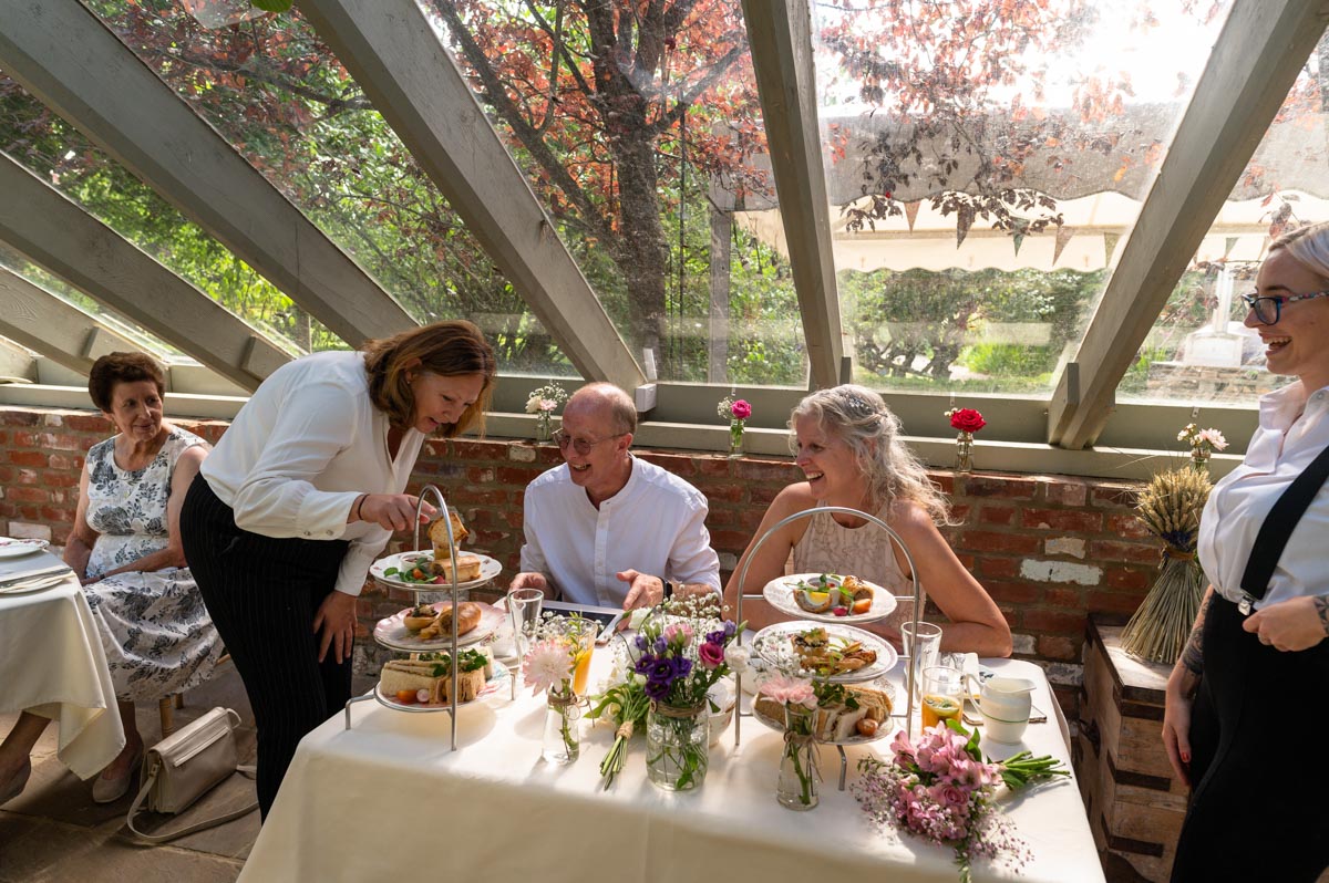 Staff at the secret garden wedding venue serve afternoon tea to jenny and phile during their reception