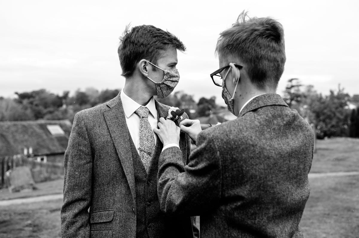 Jonathan wears a mask on his wedding day while his button hole is attached