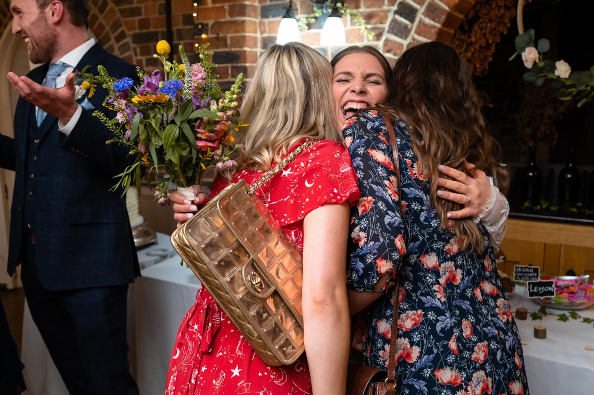 wedding photography best of 2021 wedding photograph of brider and two friends hugging after ceremony