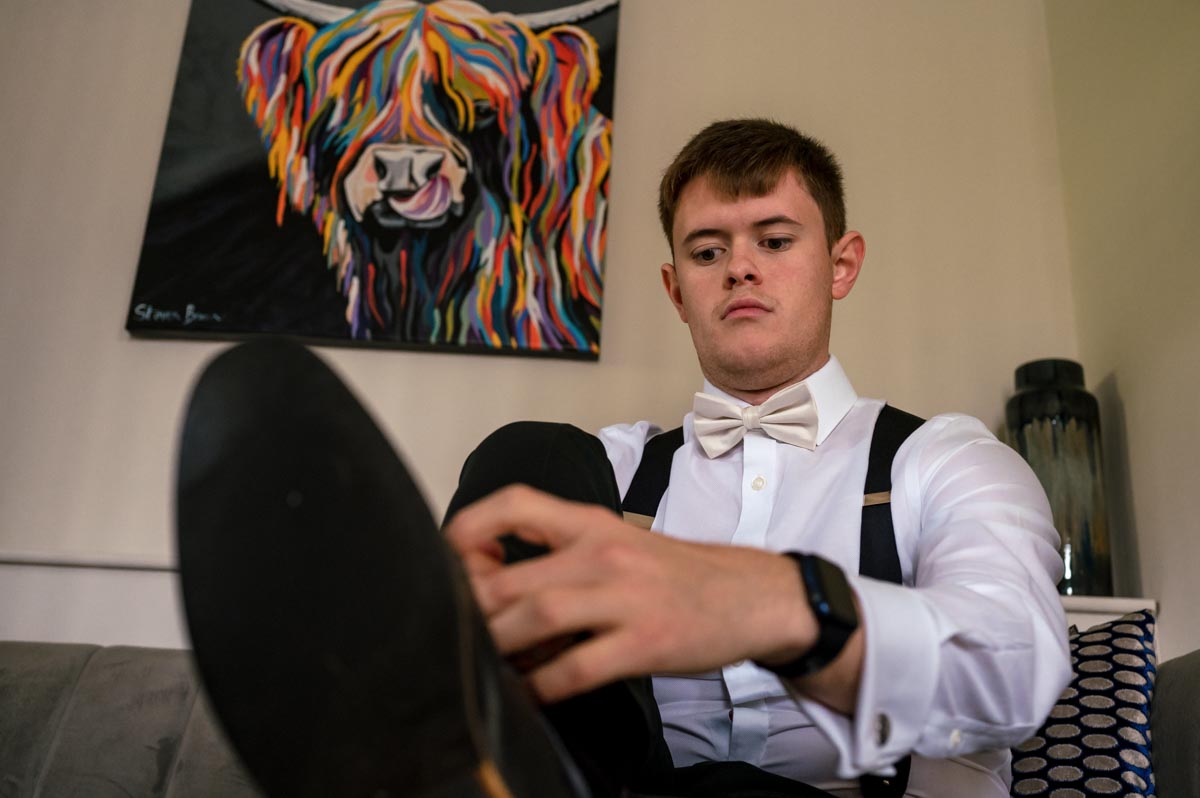 Groom tying his shoelaces before his wedding ceremony at The Oak Barn, Frame Farm venue