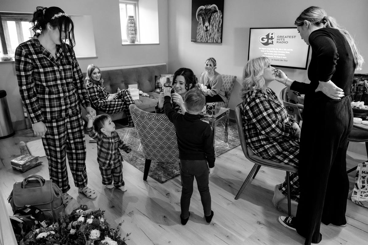 Black and white photograph of Sophia with friends and family getting ready before her wedding at The Oak Barn, Frame Farm, Kent