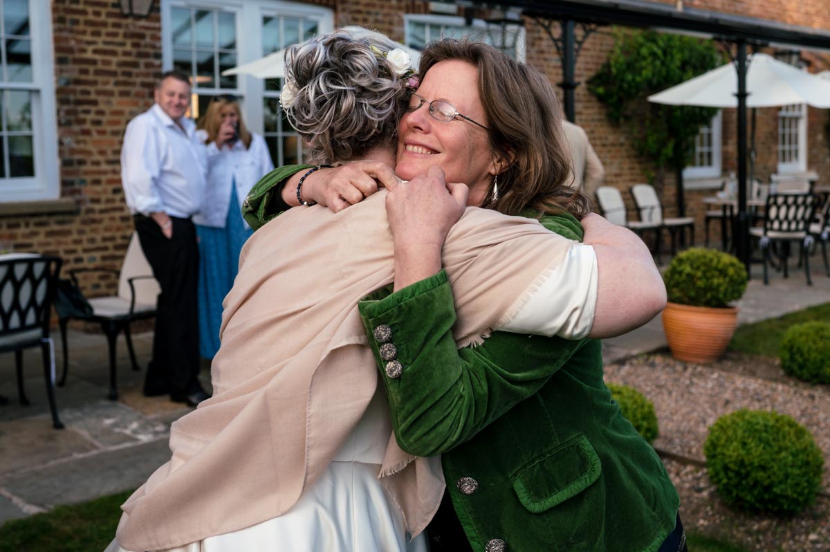 bride and friend embrace at her wedding at the secret garden wedding venue