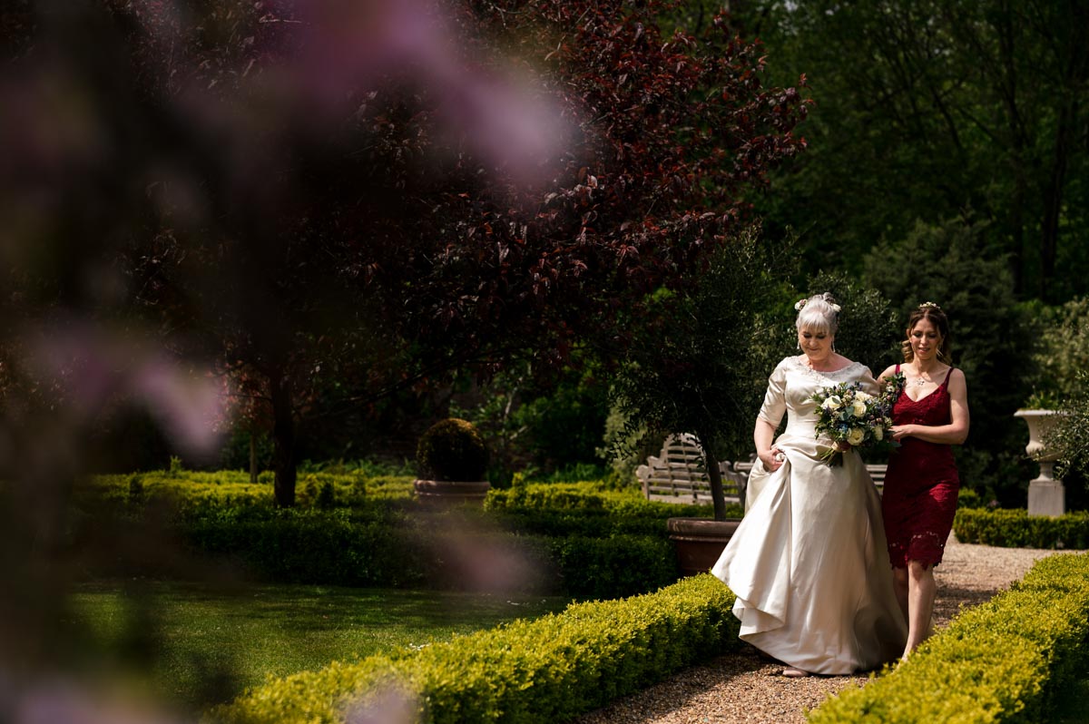 Bride Rachel and her daughter walk to gazebo at her secret garden wedding