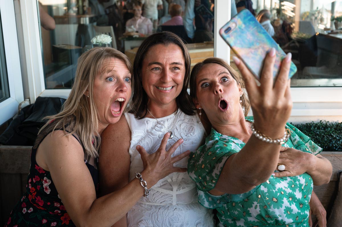 Bride and friends photographed laughing at wedding reception venue in Saltdean