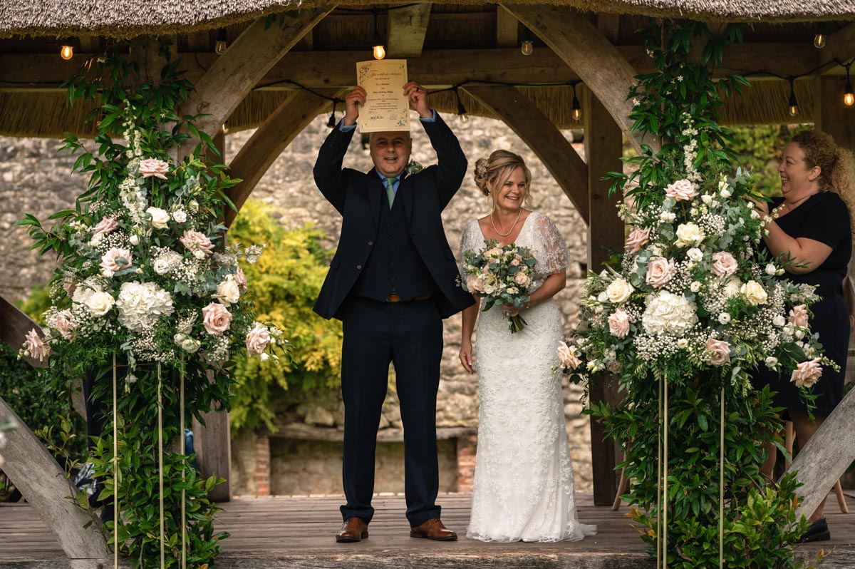 westenhanger castle wedding photography - phil holds up wedding certificate