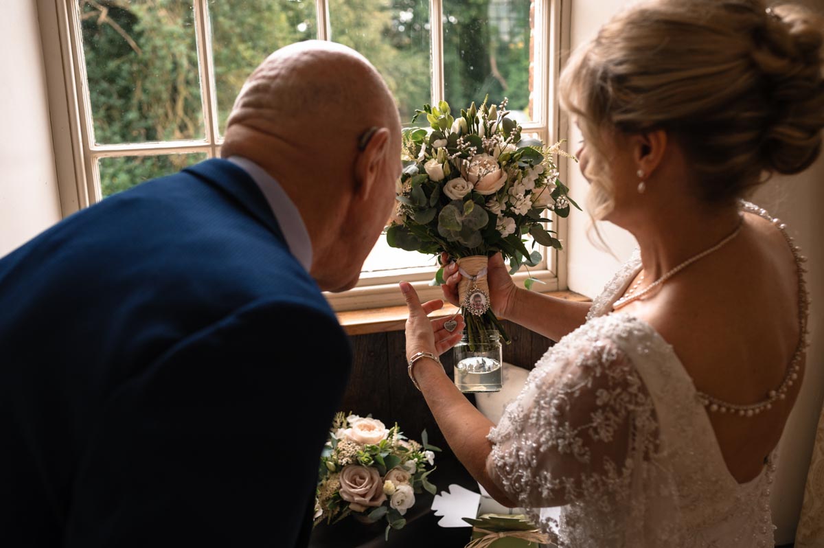 Bride shows dad photo of mum on wedding bouquet at here westenhanger castle wedding in kent