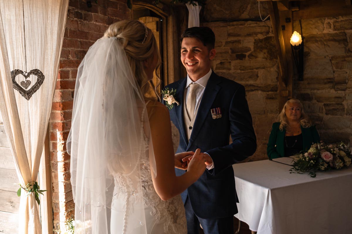 Swallows oast wedding photography. sarah places ring on james's finger